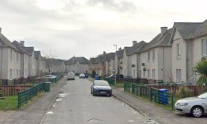 Semi detached houses on both sides with cars parked along the street.
