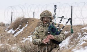 Oban's Lance Corporal Killorn from Support Company 4 Scots, plays the bagpipes from a trench. Smardan, Romania. Image: British Army