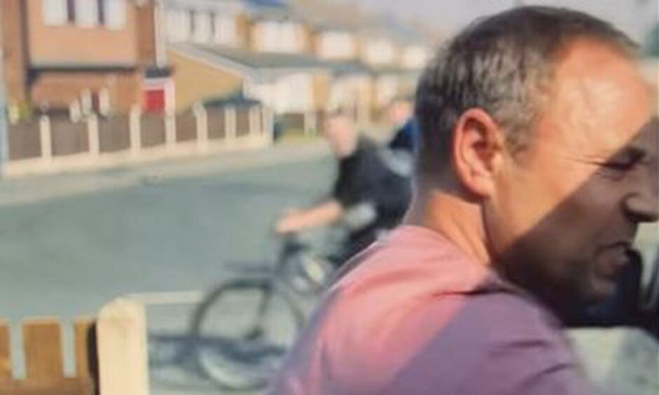 actor Stephen Graham in a close up from Adolescence, with a street and a boy on a bike in the background