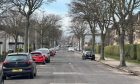 Cars parked on each side of tree lined Linksfield road in Aberdeen.