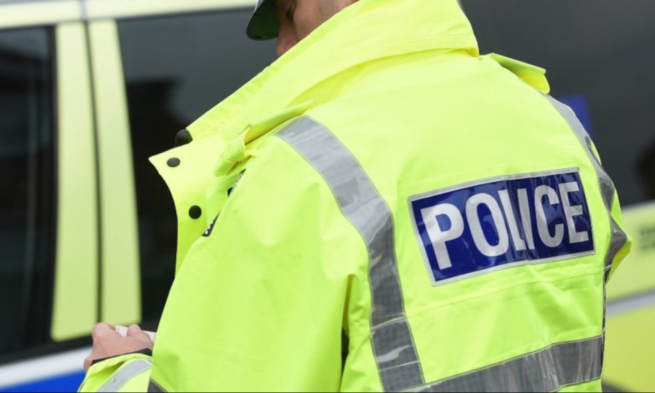 A police officer in a high-vis jacket stands with his back to the camera.