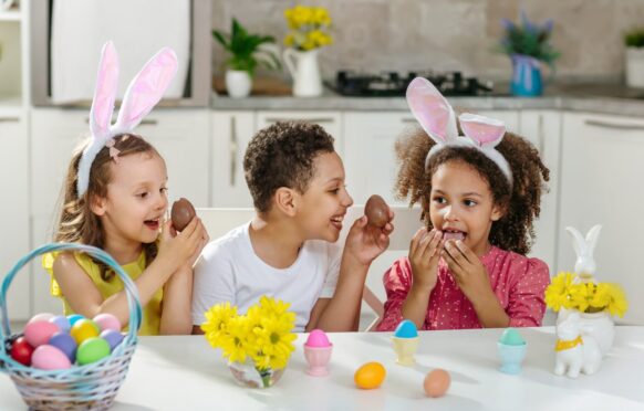 kids wearing easter bunny ears and eating chocolate eggs