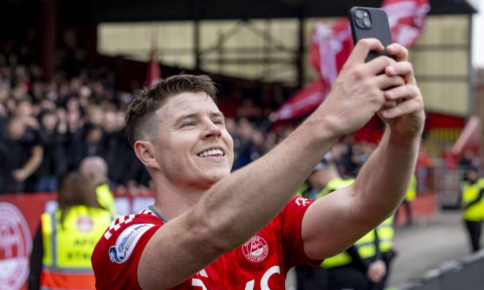 Aberdeen striker Kevin Nisbet takes a selfie in front of the Red Shed after the 1-0 win against Hibs at Pittodrie. Image by Shutterstock