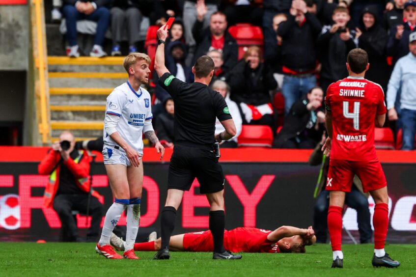 Referee Steven McLean shows a red card to Rangers' Ross McCausland during the William Hill Premiership match between Aberdeen and Rangers at Pittodrie, on April 13, 2025. Image: SNS.