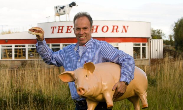 The Horn owner Kenny Farquharson holds a bacon roll and plastic pig outside the diner