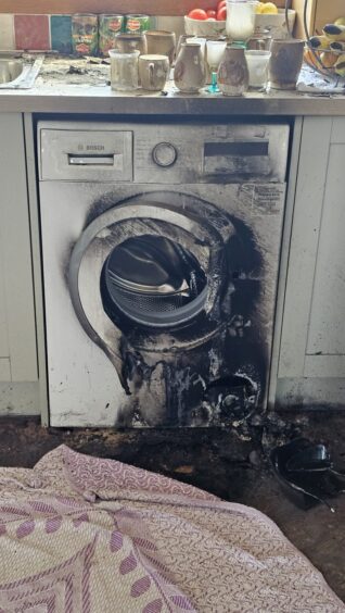 Charred washing machine covered in black following house fire.