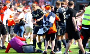 Aberdeen's Jack MacKenzie is hit with a chair from the crowd at Tannadice. Image: SNS.