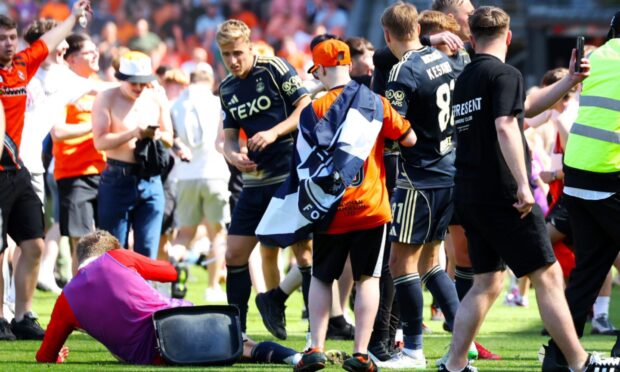 Aberdeen's Jack MacKenzie is hit with a chair from the crowd at Tannadice. Image: SNS.