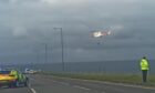 Coastguard helicopter over the water as police stand on the A90 nearby.