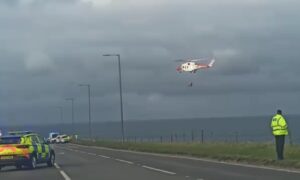Coastguard helicopter over the water as police stand on the A90 nearby.
