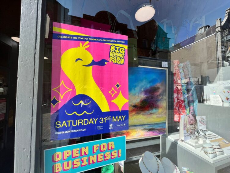 A Big Belmont Bash poster a in shop window. It sits above a sticker announcing that shops are "open for Business!" during the ongoing Union Street improvements.