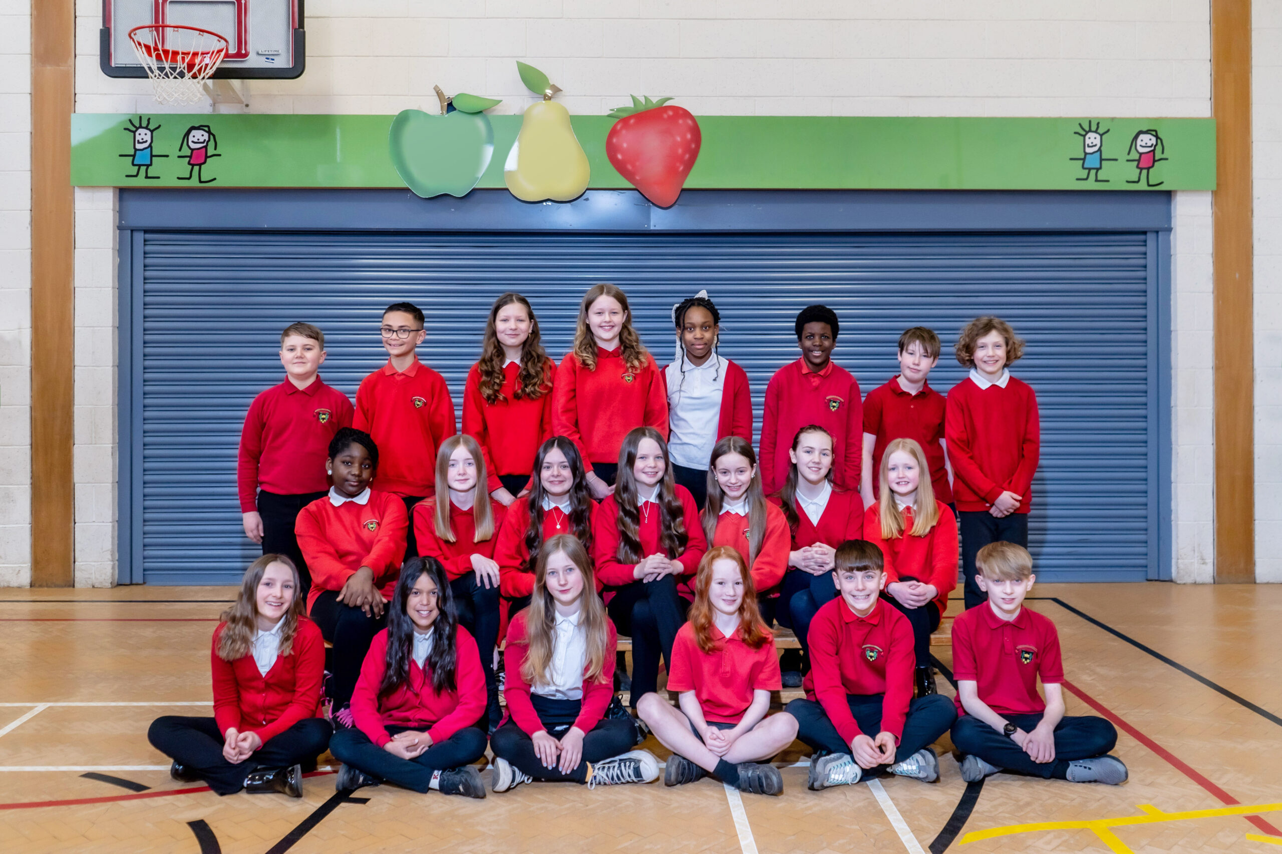 Three rows of school pupils in red sweatshirts.