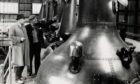 1962: Small stills and slow distillation is the recipe for good whisky which they still believe in at Glenfiddich Distillery, Dufftown. Here Mr MC Naughton, the assistant manager, and Mr Macdonald the brewer are seen against a background of seven of Glenfiddich's twelve stills. Image: DC Thomson