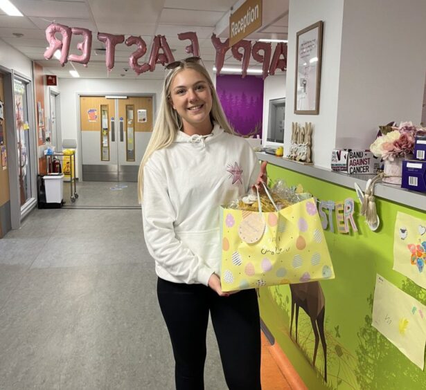 Emma in hospital ward delivering bag of treats. 