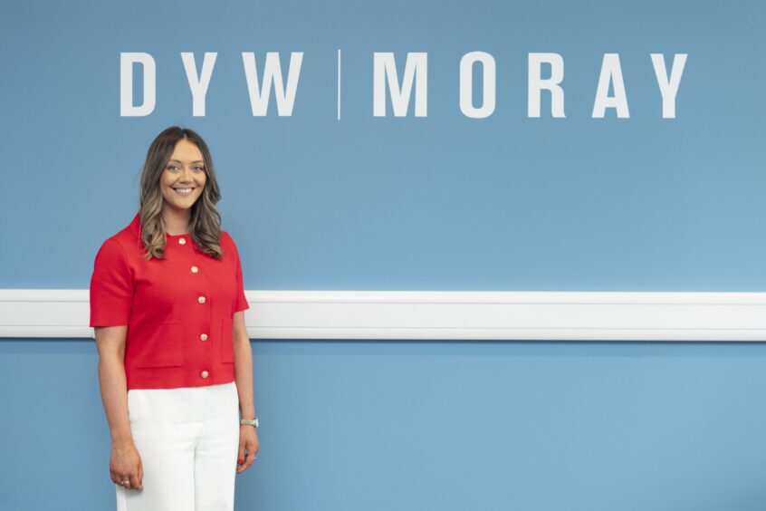 Aimee standing in front of DYW Moray sign. 
