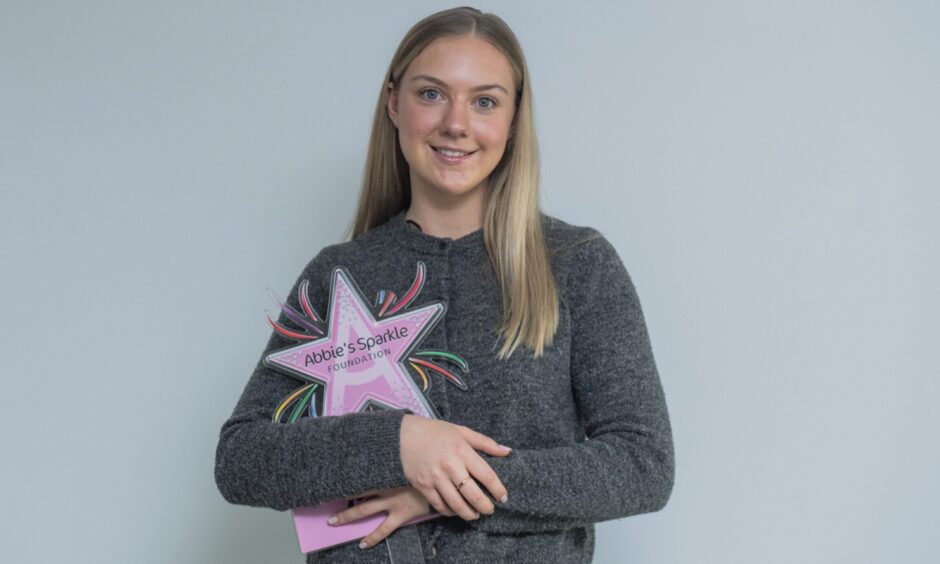 Emma Whitton holding Abbie's Sparkle Foundation logo.