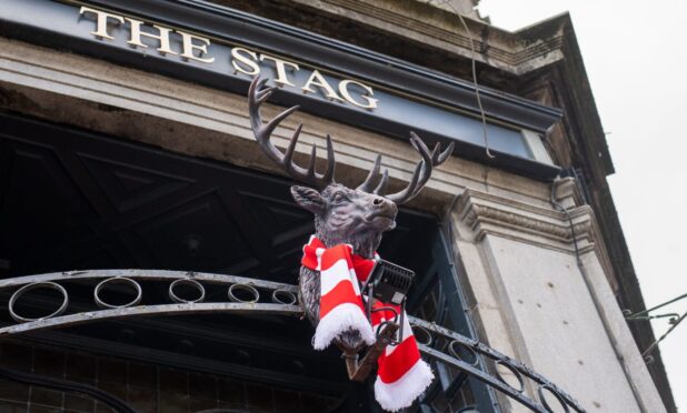 Red and white scarf around stag outside pub