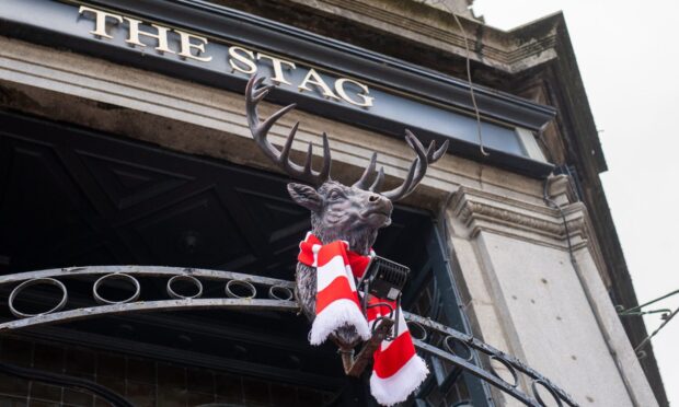 Red and white scarf around stag outside pub
