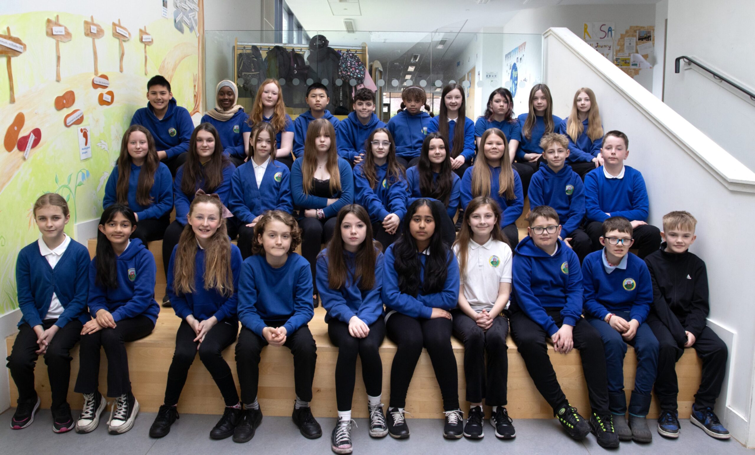 Three rows of pupils in royal blue tops in a school.