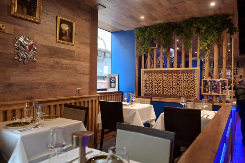 Restaurant decorated in dark blue walls and brown wooden panelling.