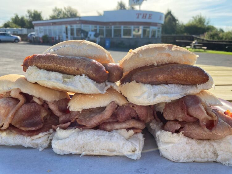 A selection of bacon rolls and rolls with sausage, with The Horn in the background.