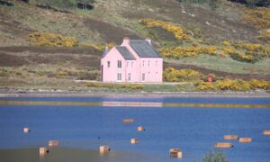 Coffins floating on Loch Glass, with a large pink house in the background.