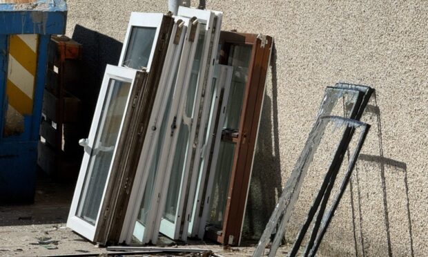 Windows outside leaning against a wall.