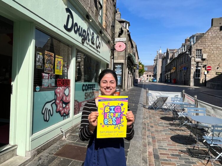 Daniela Troncoso holding a poster for Big Belmont Bash outside Dough & Co.