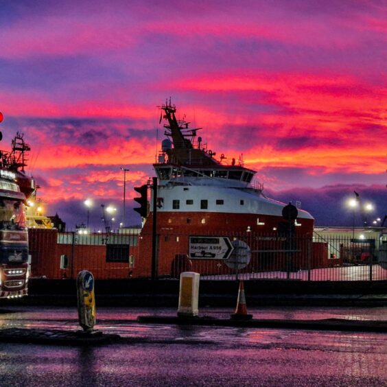 A vibrant sunset turns the sky above Aberdeen harbour purple, pink and orange.