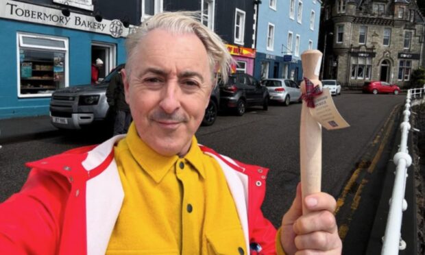 Alan Cumming with a porridge spurtle outside Tobermory Bakery. Image: Alan Cumming/ Instagram.