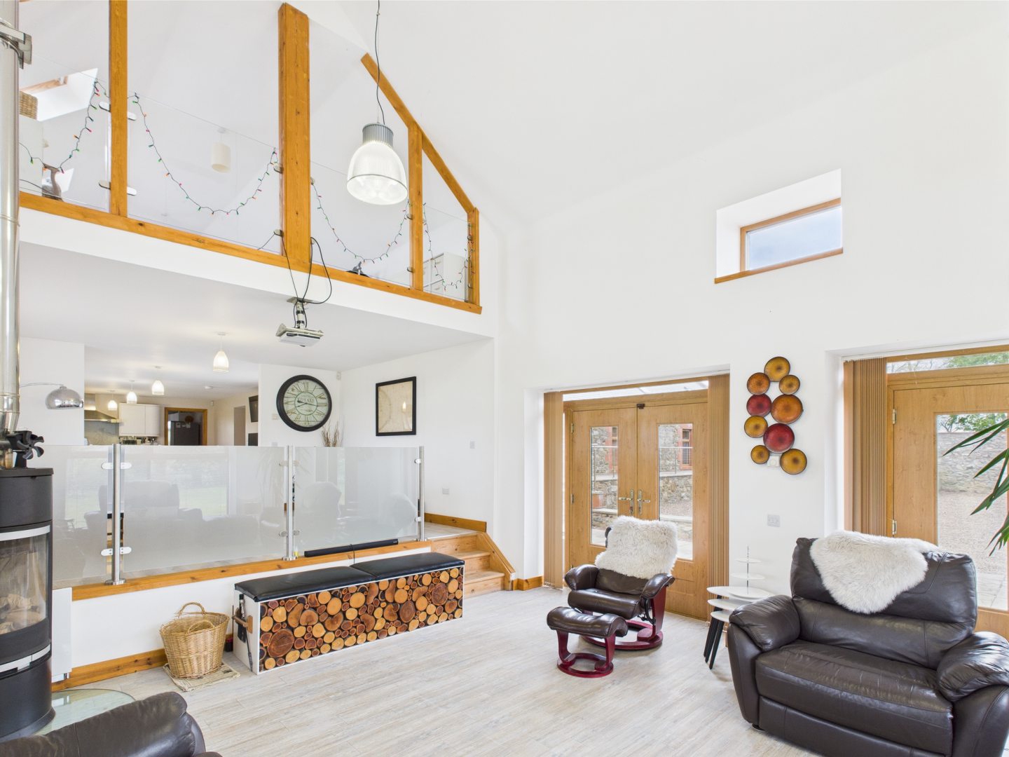 The interior of The Steadin, with white walls and light wood and a glass wall to the master bedroom upstairs
