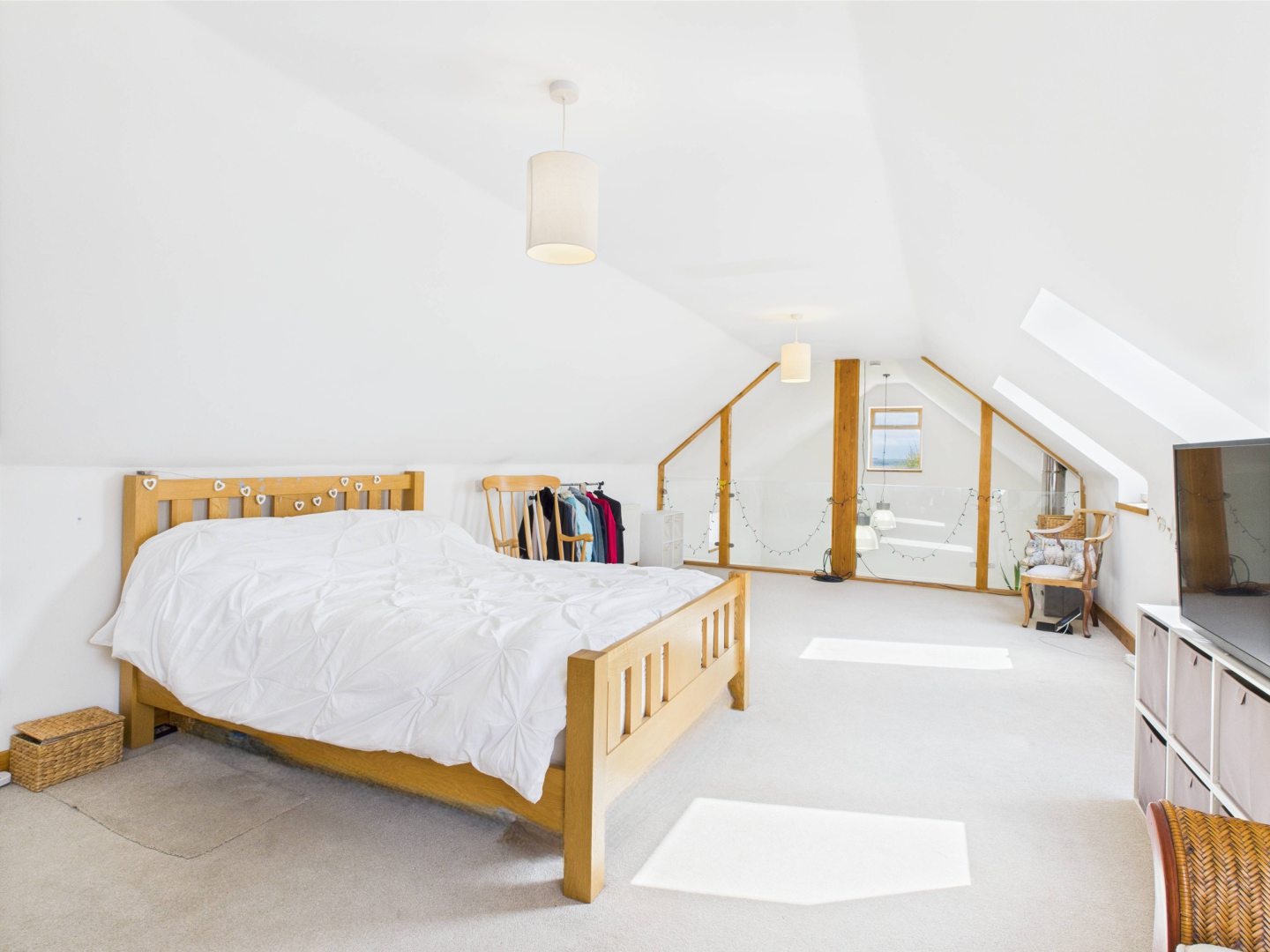 The master bedroom with the glass wall showing, a light wooden double bed and white walls
