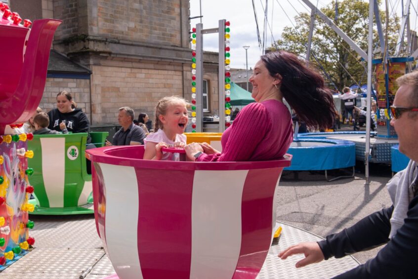 Adults and children having fun on the teacup ride at the Feein' Market in Stonehaven.