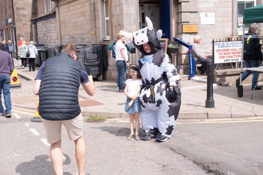 A child getting her photo taken with a man dressed as a cow at the Feein' Market in Stonehaven.