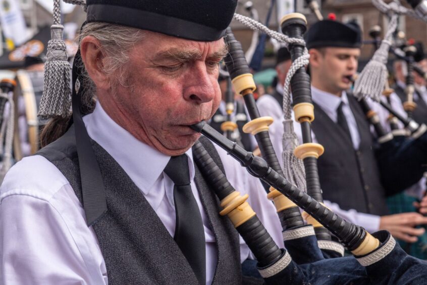 A piper blows into the pipes.