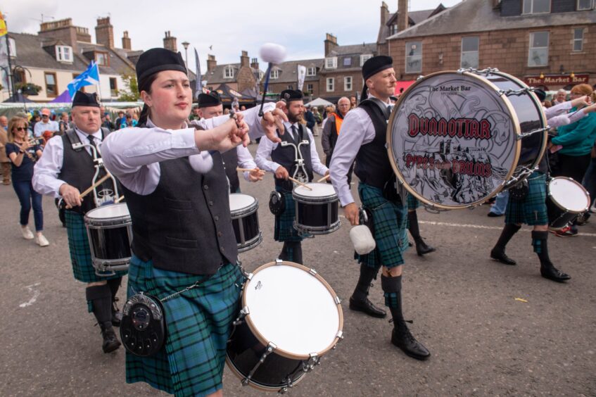Drummers with a drum saying "Dunnottar Pipes and Drums".