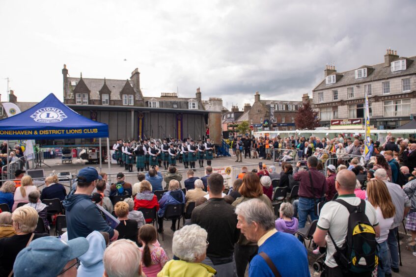 A large crowd of people watch the pipers.