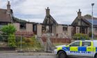 Police car outside fire damaged homes in Ballater