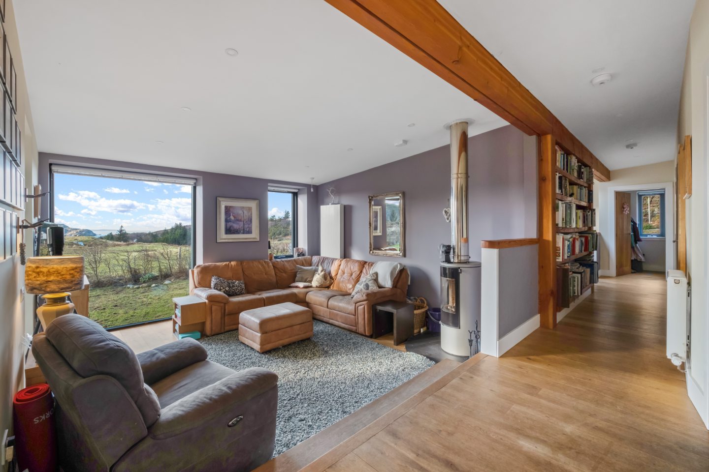 The living room is painted in a muted purple that complements the natural landscape seen through the picture window.