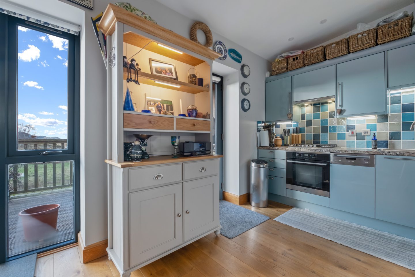 The annexe kitchen has wood floors and blue cupboards.