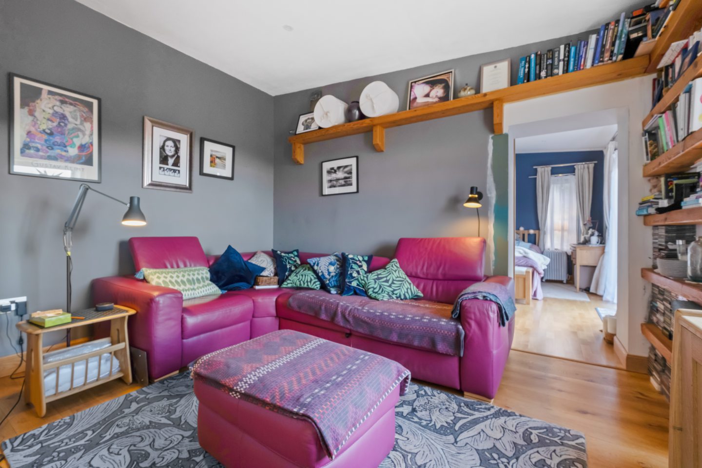 The snug has grey walls and wood floors. There are chunky wooden shelves on one wall.
