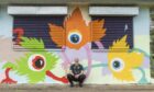 Artist Duncan Wilson sitting in front of sports pavilion.