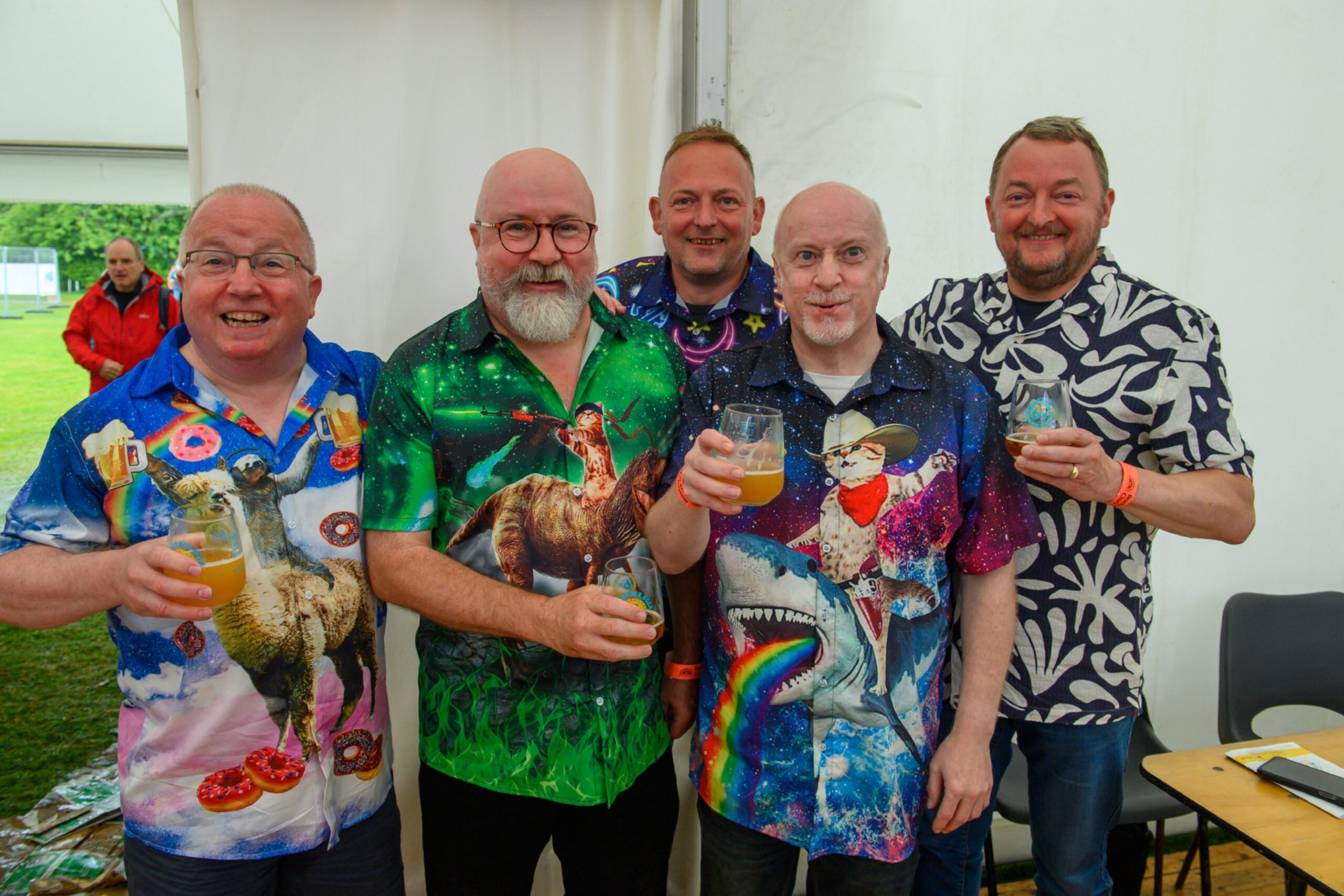 Five men in colourful shirts pose with beer in hand