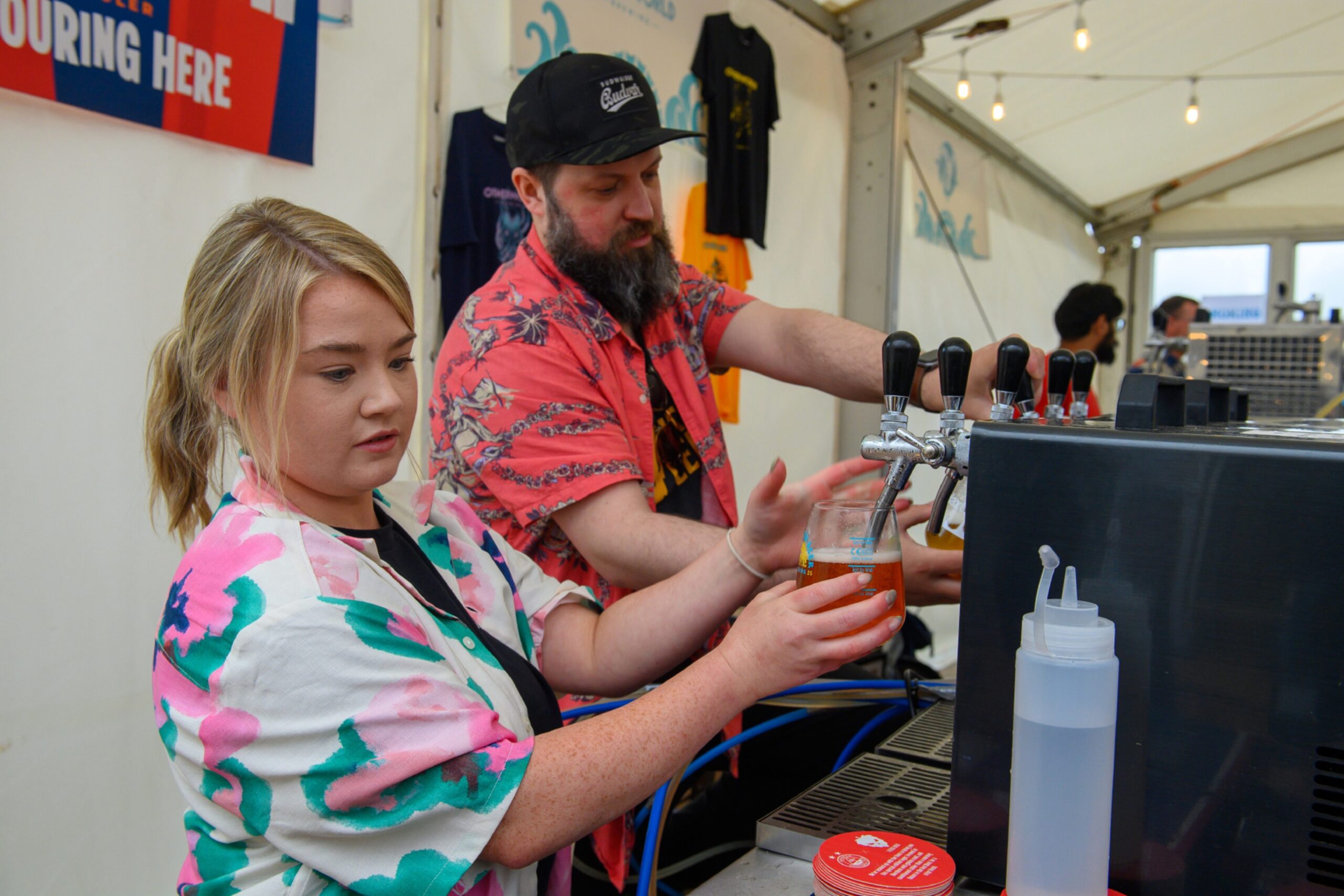 Two bartenders pour draught beers
