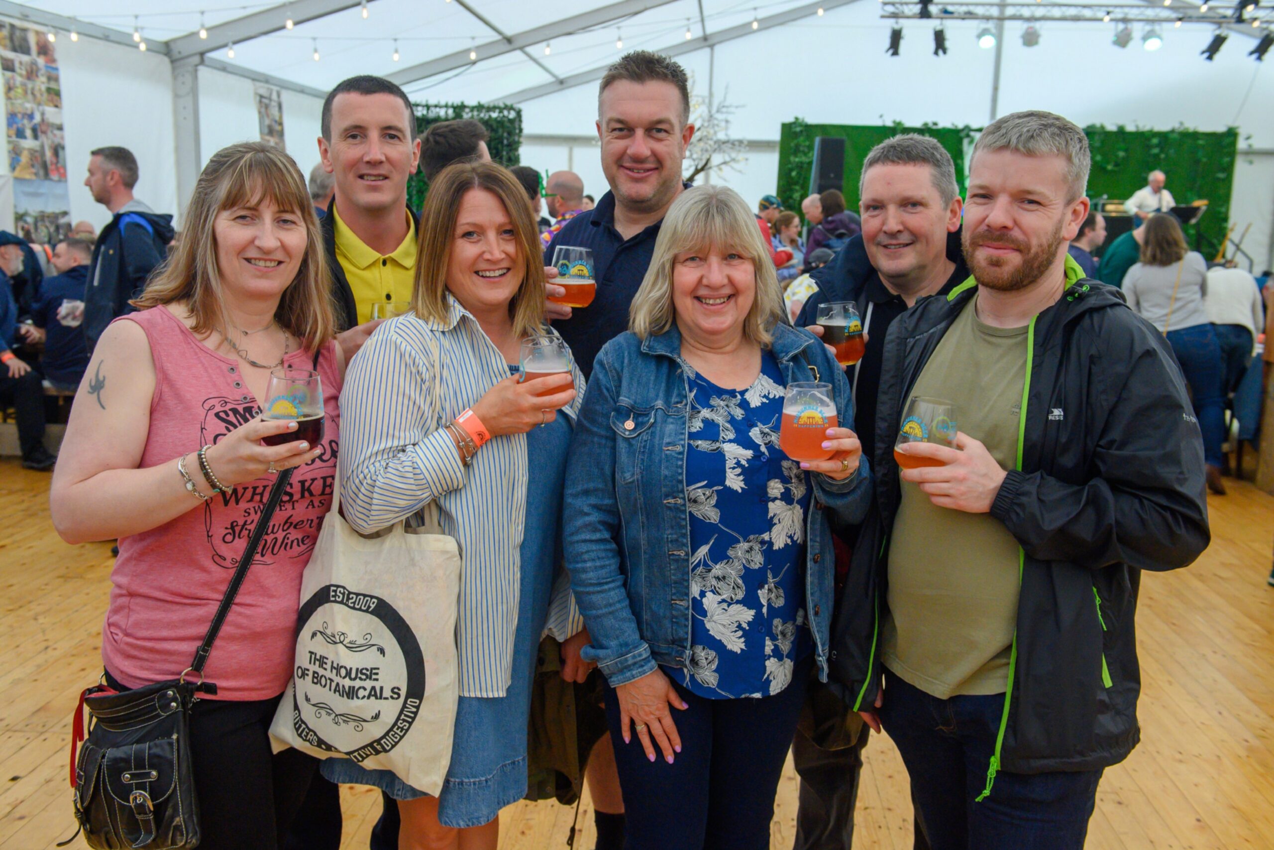 A group of seven people, all with a drink in hand