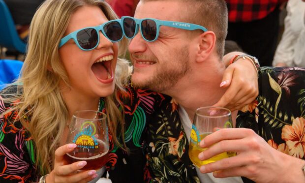 A woman and man laughing with beer in hand