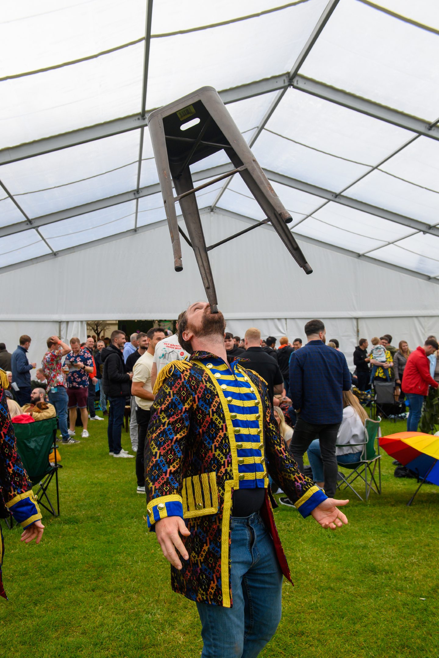 Man dressed as a ringmaster balances a bar stool on his chin