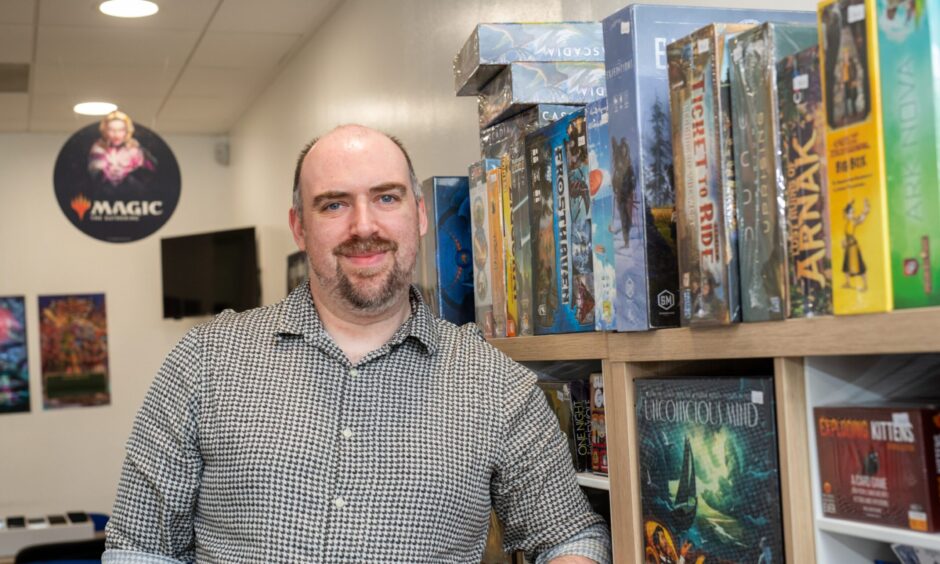 Stuart standing in front of shelves full of tabletop games
