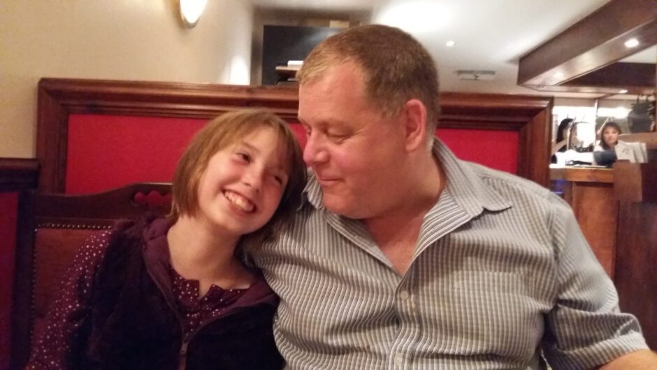 A per-teen girl leaning on a man's shoulder and smiling up at him. He is smiling back at her.