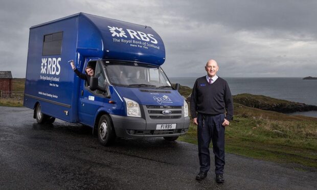 Ruaridh Murray standing in front of the Lewis and Harris mobile banking van which displays RBS livery.